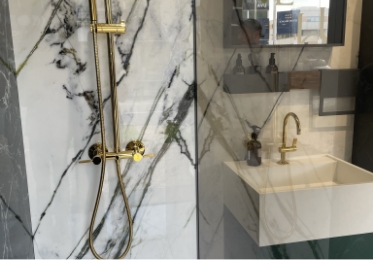 intérieur douche avec mur en marbre blanc et robinetterie or